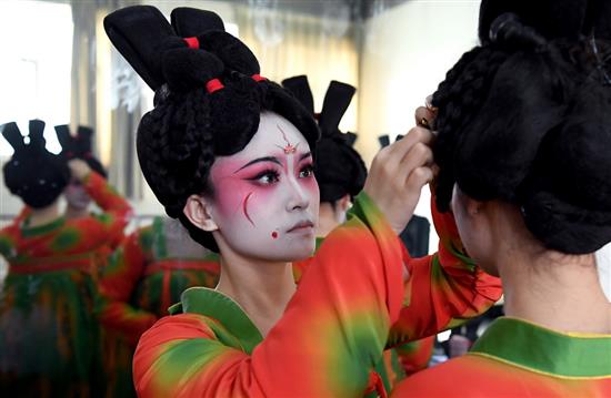 ?郑州歌舞剧院的演员帮同事整理假发（2月20日摄）。